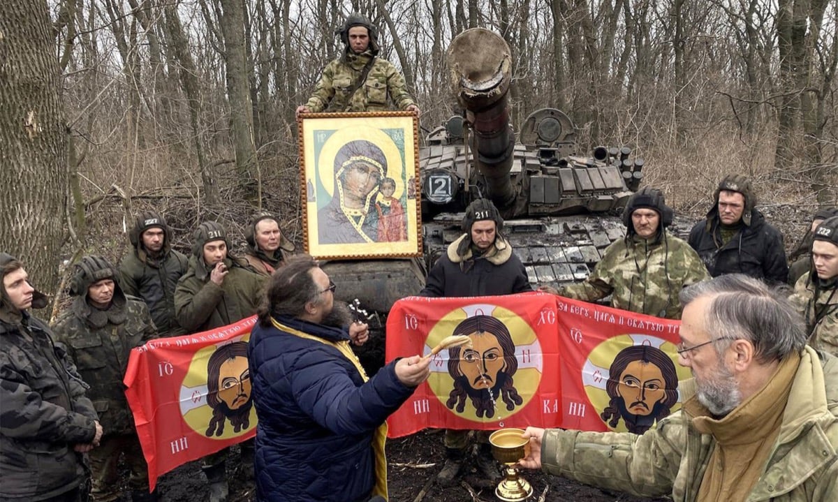 A priest splashes holy water on Russian servicemen gathered around Orthodox icons before a tank in the Luhansk region of eastern Ukraine