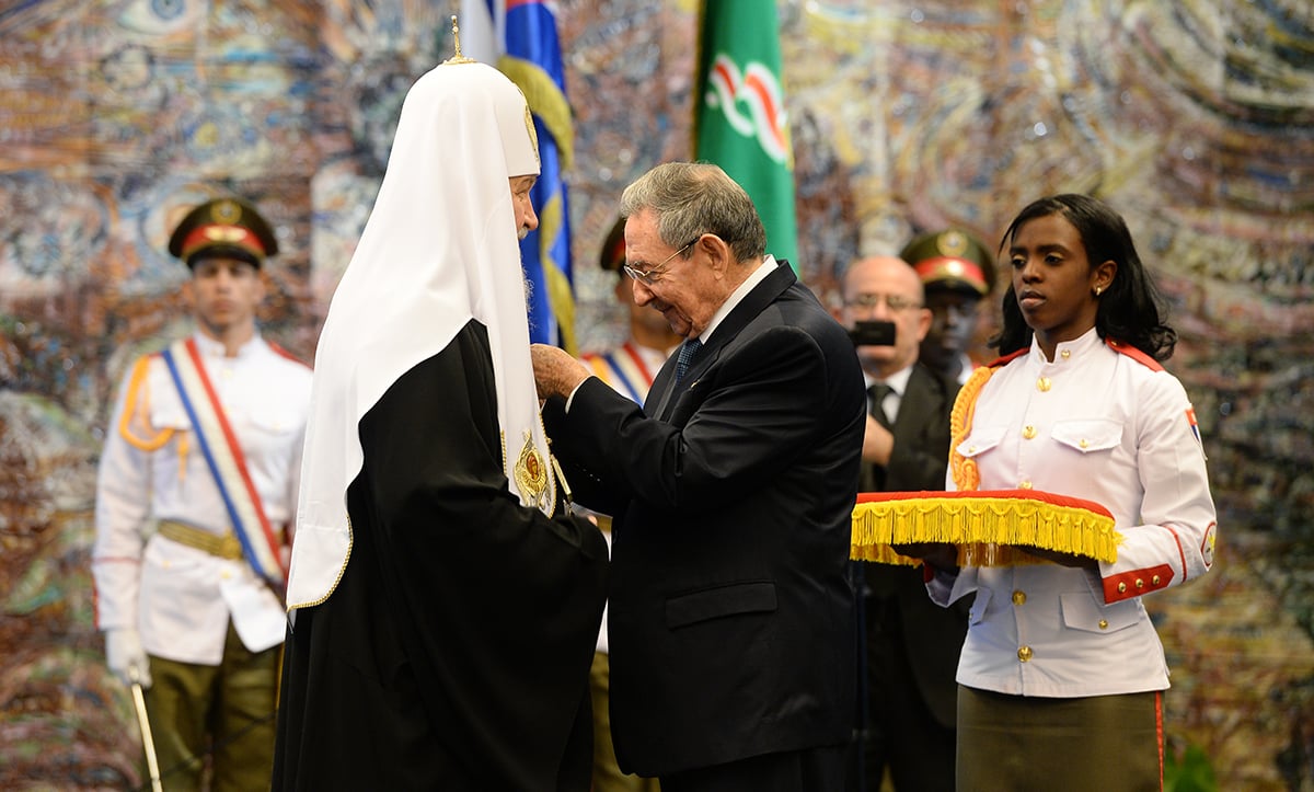 Raúl Castro pinning the Order of José Martí on Patriarch Kirill at the Palace of the Revolution in Havana, February 13, 2016, with Cuban military honor guard and an aide holding the medal cushion