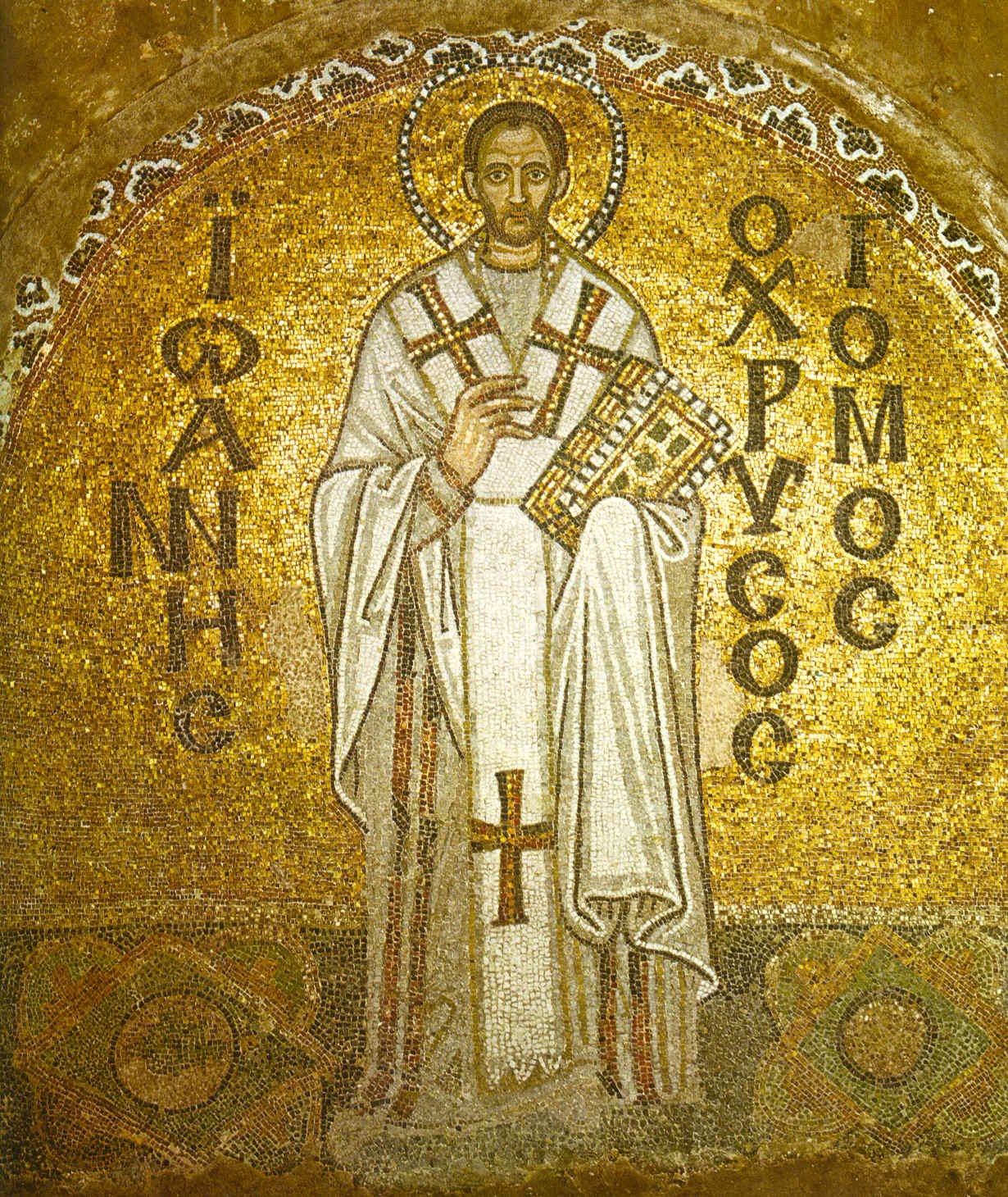 Byzantine mosaic of St. John Chrysostom in white vestments holding a jeweled Gospel book, with a golden halo and Greek inscription