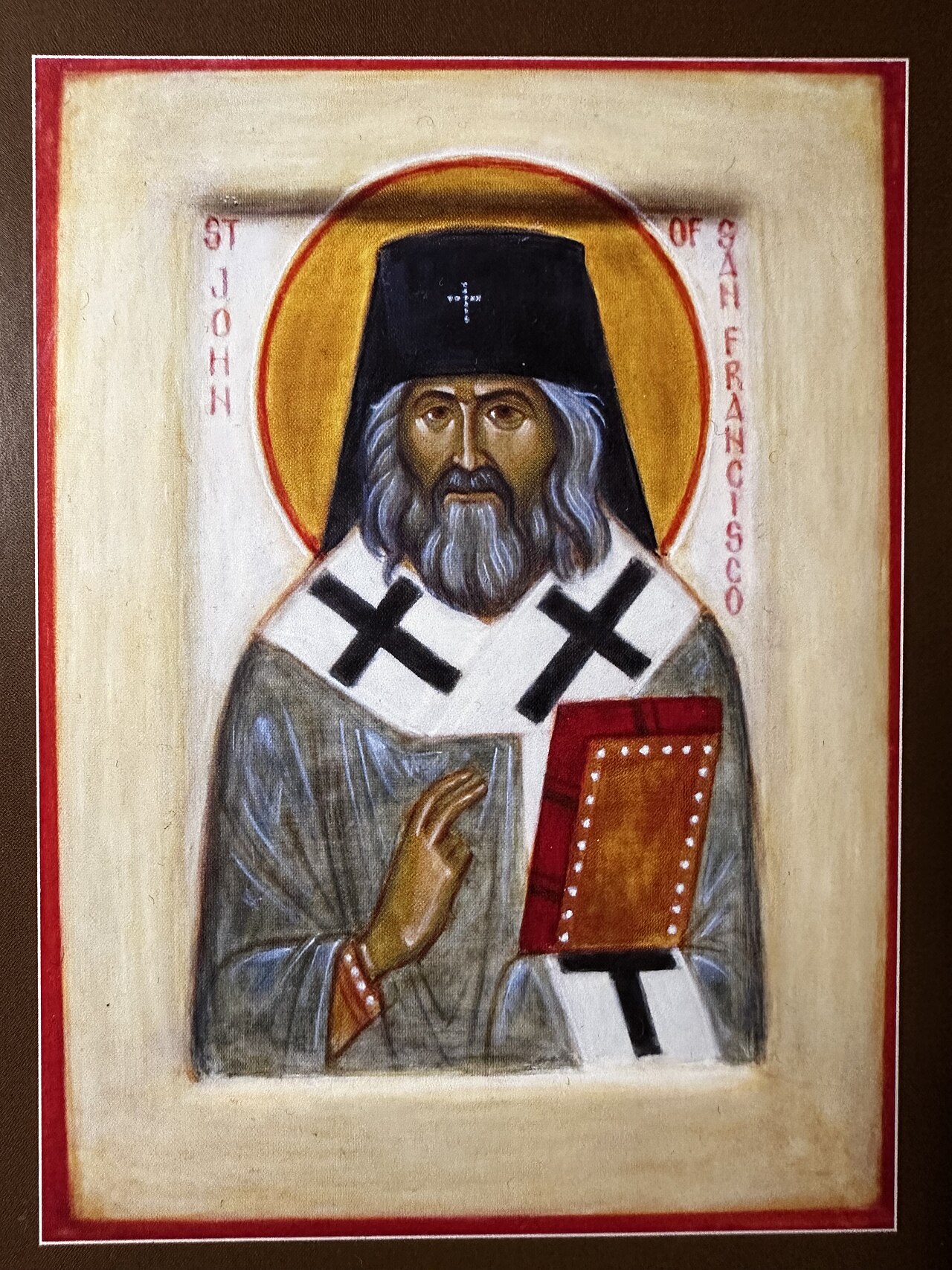 Icon of St. John of Shanghai and San Francisco depicting him in black hierarchical vestments with a golden halo, holding a Gospel book
