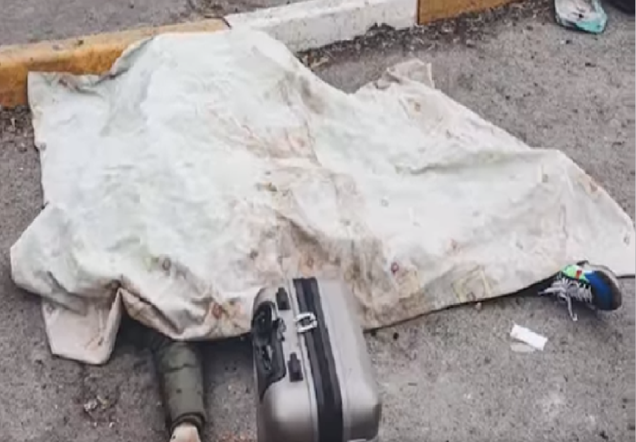 Body of a civilian killed while evacuating Irpin, suitcase beside the covered body on the road