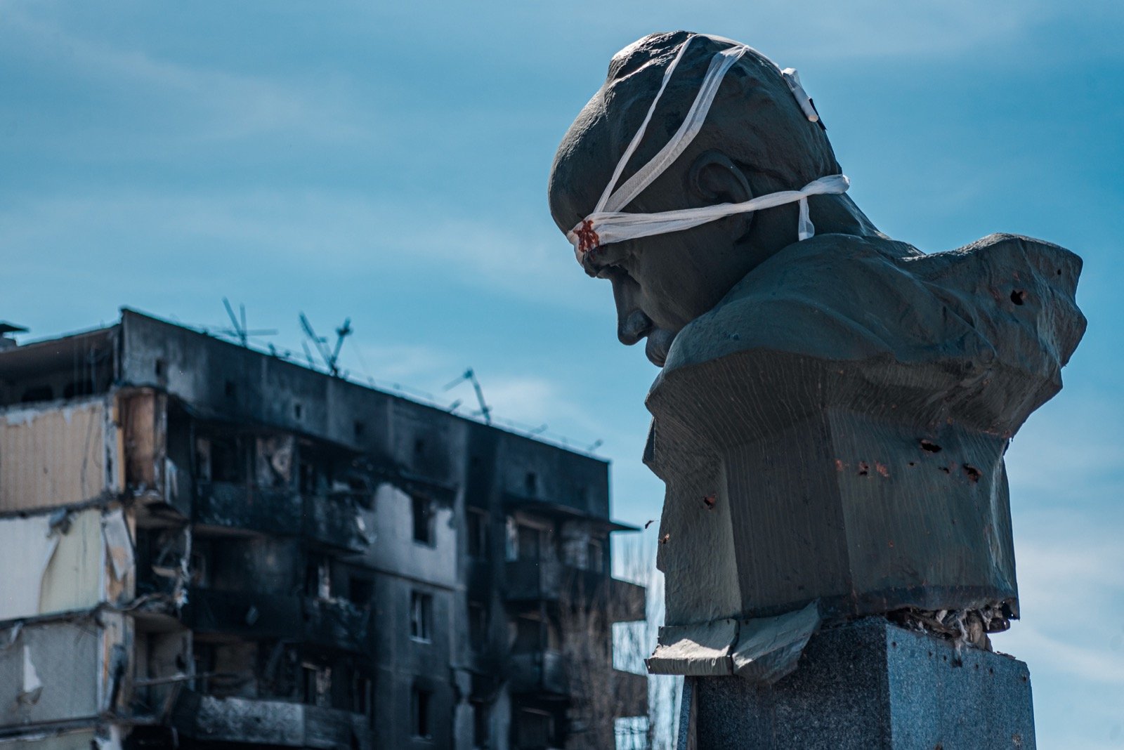 Destroyed apartment building in Borodianka with damaged Shevchenko monument in the foreground