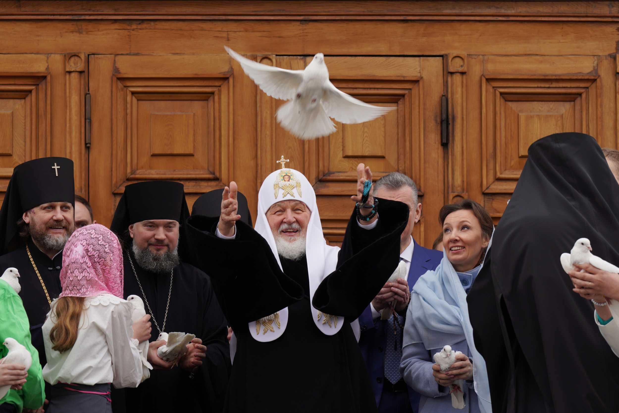 Patriarch Kirill releasing a white dove on the steps of the Annunciation Cathedral in the Moscow Kremlin, surrounded by clergy and faithful