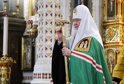 Patriarch Kirill processing through the Cathedral of Christ the Saviour in green liturgical vestments, holding his patriarchal staff.