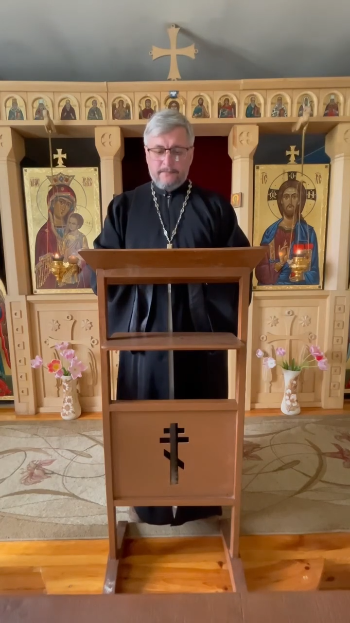 Archpriest Andriy Pinchuk speaking at a church ambo with icons of the Theotokos and Christ flanking him